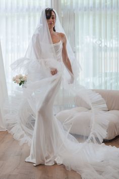 a woman in a white wedding dress is standing on the floor with her veil over her head