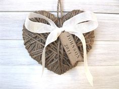 a heart shaped ornament hanging on a white wooden wall with a ribbon tied around it