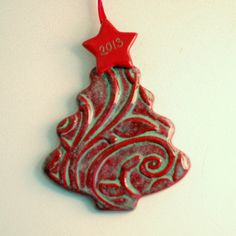 a red and white ornament with a star on it's top hanging from a string