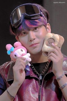 a young man wearing goggles and holding two stuffed animals