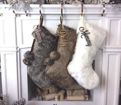 three stockings hanging from hooks in front of a fireplace decorated with ornaments and snowflakes