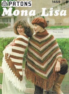 two women standing next to each other wearing knitted ponchles and scarves