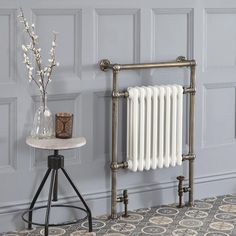 a white radiator next to a table and vase with flowers on the side