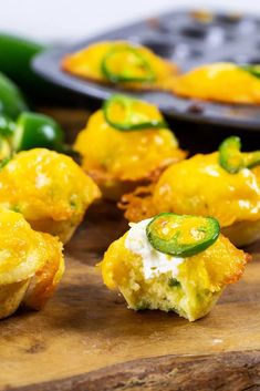 some food that is sitting on a wooden cutting board next to green peppers and a muffin