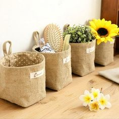 three burlap baskets with plants in them on a wooden table next to a wall