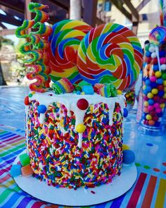 a birthday cake decorated with sprinkles and lollipops on a table