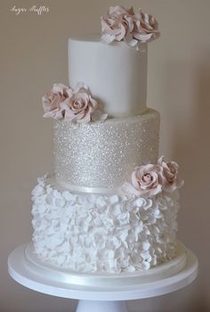 a three tiered white wedding cake with pink flowers on the top and bottom layer