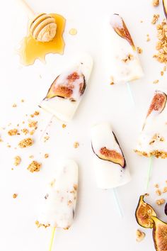 an assortment of popsicles with toppings and honey on white background, top view