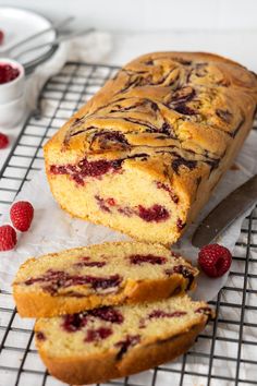 a loaf of raspberry bread sitting on top of a cooling rack next to some berries