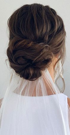 the back of a woman's head with a veil over her shoulder, wearing a wedding dress