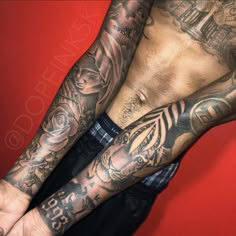 a man with many tattoos on his arms and chest is posing for the camera in front of a red background