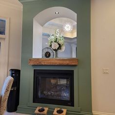 a fireplace in a living room with a clock on the mantle and flowers sitting on top