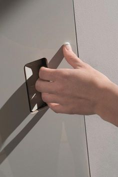 a person's hand holding onto a door handle on a gray wall with white trim