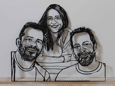 a paper cutout of three men and a woman sitting next to each other on top of a wooden table