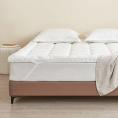 a bed with white sheets and pillows in a room