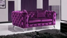 a purple couch sitting on top of a white floor next to a black and white rug