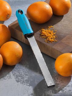 an orange peeler sitting on top of a cutting board next to some oranges