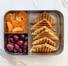 a lunch box with sandwiches, fruit and oranges