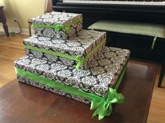 three boxes with green bows are stacked on top of each other in front of a piano