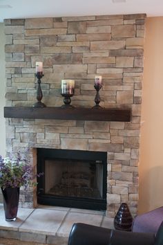 a stone fireplace in a room with wood flooring and pictures on the wall above it