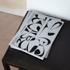 an open book sitting on top of a table next to a black and white wall