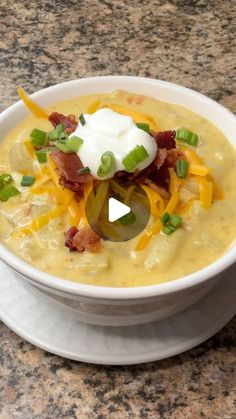 a white bowl filled with soup and topped with sour cream, green onions and bacon