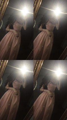 a woman in a pink dress looking at her reflection in a mirror with the light shining through it