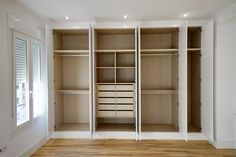 an empty closet with white shelves and drawers in the middle, next to a window