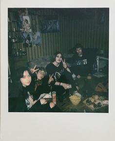 three people sitting on the floor with food and drinks in front of them, posing for a photo