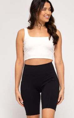 a woman wearing black shorts and a white crop top