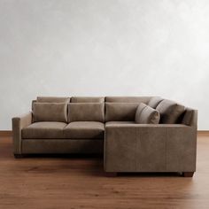 a large sectional couch sitting on top of a wooden floor next to a white wall