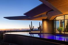 an outdoor swimming pool in front of a large house with cactus and cacti