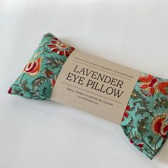 a blue and red flowered eye pillow sitting on top of a white table