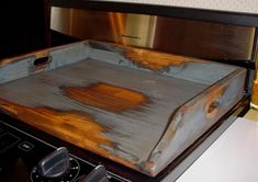 an old wooden box sitting on top of a stove next to a bottle of beer