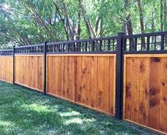 a wooden fence with metal railings in the grass