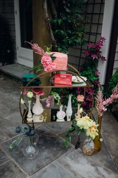 a table topped with vases filled with flowers next to a brick wall and door