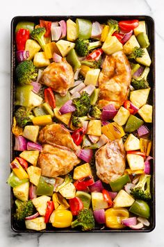 chicken, broccoli, and peppers in a baking pan on a marble surface