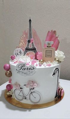 a white cake with pink decorations and the eiffel tower in paris on top