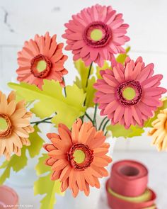 colorful flowers are in a vase with spools of thread