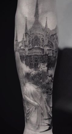 a man's leg with a black and white tattoo design on it, featuring a statue in front of a castle