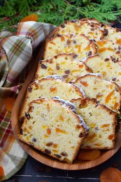 slices of cake sitting on top of a wooden plate next to carrots and herbs