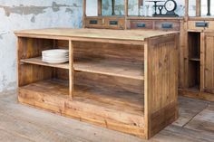 a wooden table with plates on it in front of a mirror and cabinets that are made out of wood