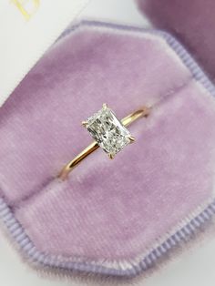 an engagement ring with a princess cut diamond on it in a velvet box, close up