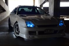 a white car parked in a parking garage with blue lights on it's hood