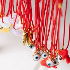 red string with evil eyes hanging from it's ends and some beads attached to them