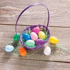 an easter basket filled with colored eggs on top of a wooden table