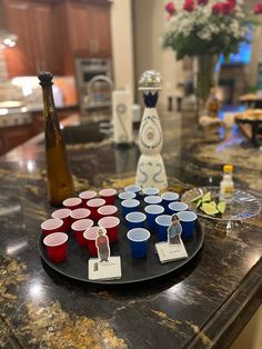 a table topped with cups and plates filled with drinks on top of a marble counter