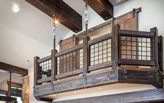 a large wooden window hanging from the ceiling in a room with exposed beams and wood flooring