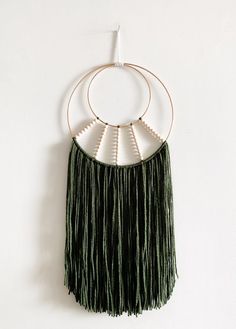 a green and white wall hanging with fringes