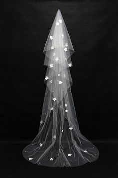 a wedding veil with white flowers on the bottom and stars on the bottom, in front of a black background